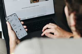 man achter laptop met mobiele telefoon